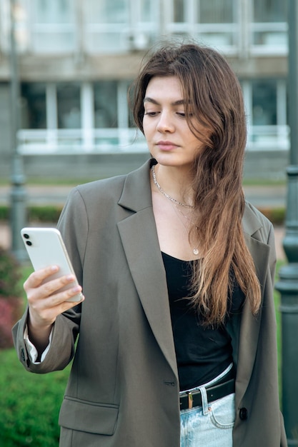 Mujer joven de negocios con un teléfono inteligente en un fondo borroso de la ciudad