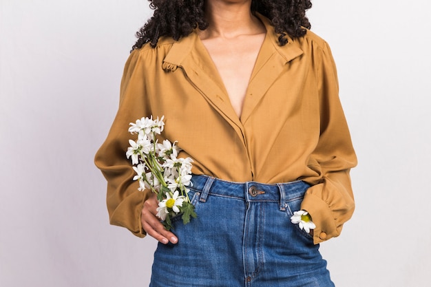 Foto gratuita mujer joven negra con flores de margarita en el bolsillo de los pantalones vaqueros