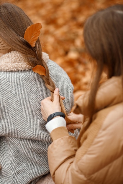 mujer joven, y, niña, en, otoño, bosque, mujer, tejer, un, trenza, para, ella, hija, niña, llevando, moda, chaqueta gris