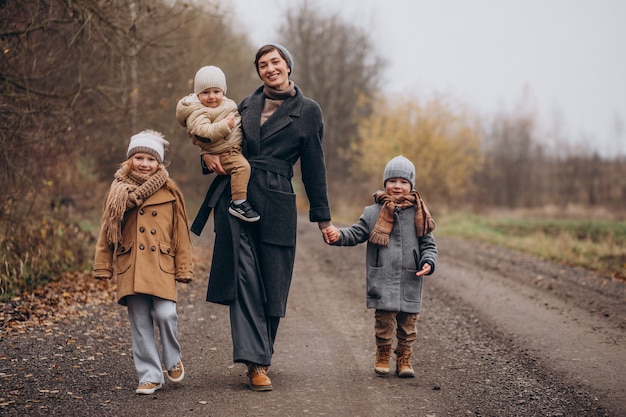 Foto gratuita mujer joven con niños caminando en el parque otoño