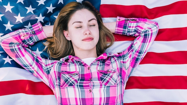 Mujer joven con los ojos cerrados acostado en la bandera de Estados Unidos