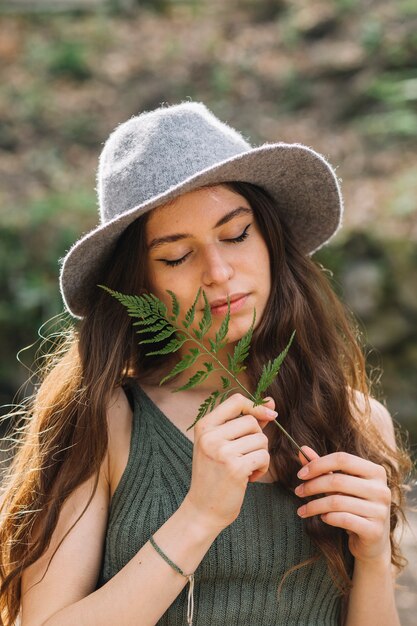 Mujer joven oliendo una hoja en el bosque