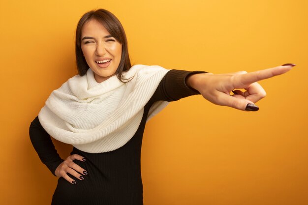 Mujer joven con pañuelo blanco feliz y alegre sonriendo apuntando con el dedo índice a algo