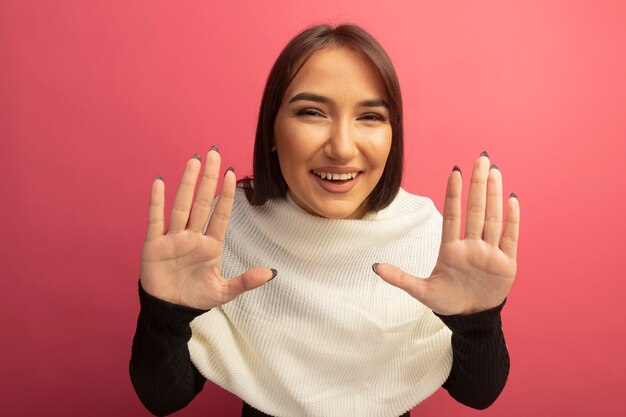 Mujer joven con pañuelo blanco levantando las manos en rendición sonriendo alegremente