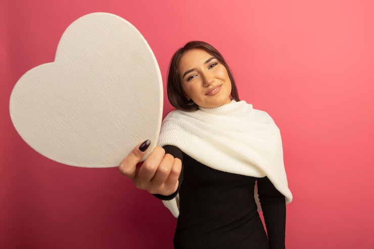 Foto gratuito mujer joven con pañuelo blanco mostrando corazón de cartón sonriendo cariñosamente