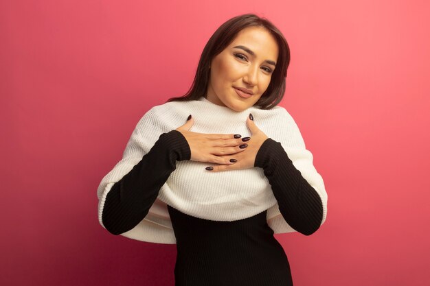 Mujer joven con pañuelo blanco sosteniendo la mano sobre su pecho feliz y positivo sentimiento agradecido