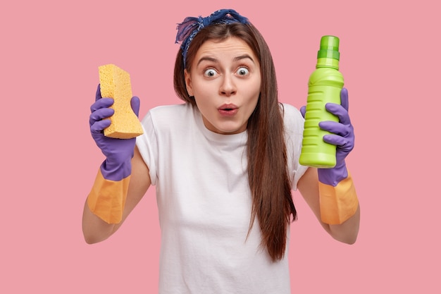 Mujer joven con pañuelo en la cabeza sosteniendo productos de limpieza