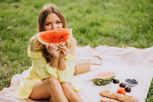 Mujer joven en el parque comiendo sandía