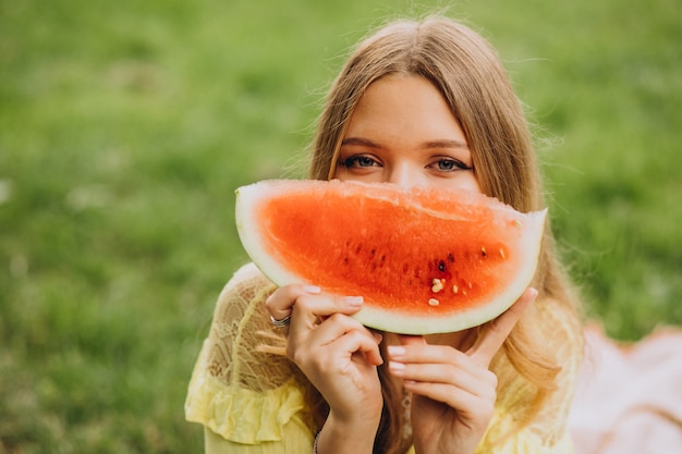 Mujer joven en el parque comiendo sandía