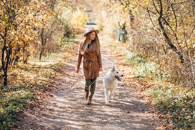 Mujer joven en el parque con su perro blanco