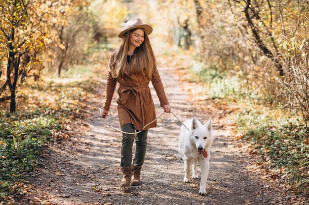 Mujer joven en el parque con su perro blanco