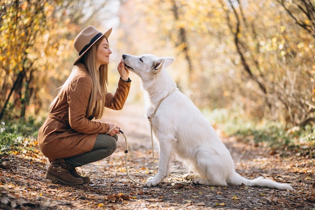 Mujer joven en el parque con su perro blanco