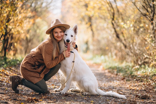 Mujer joven en el parque con su perro blanco