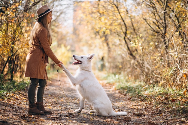 Mujer joven en el parque con su perro blanco