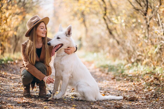 Mujer joven en el parque con su perro blanco