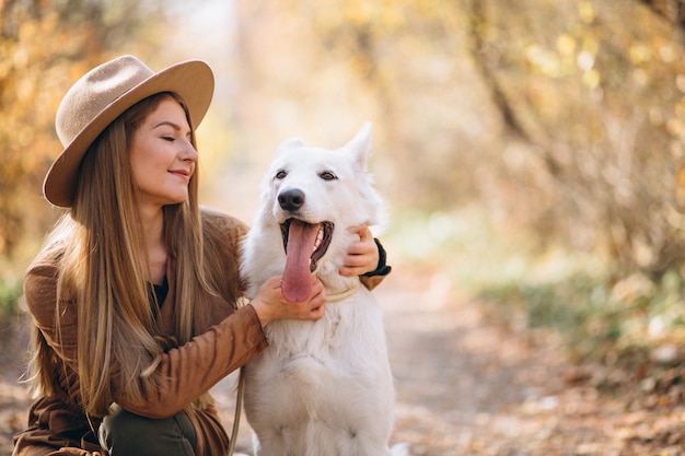 Mujer joven en el parque con su perro blanco