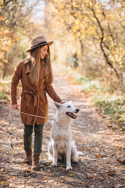 Mujer joven en el parque con su perro blanco