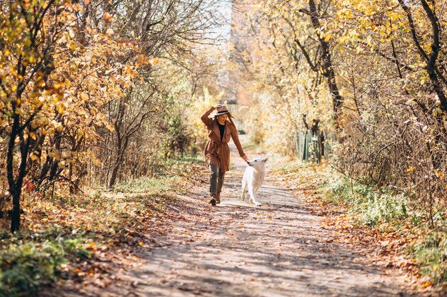 Mujer joven en el parque con su perro blanco