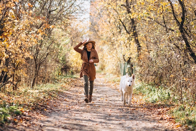 Mujer joven en el parque con su perro blanco