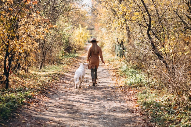 Mujer joven en el parque con su perro blanco