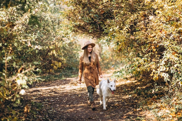 Mujer joven en el parque con su perro blanco