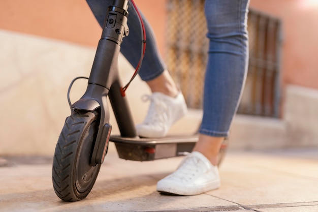 Mujer joven paseos en un scooter eléctrico en la ciudad