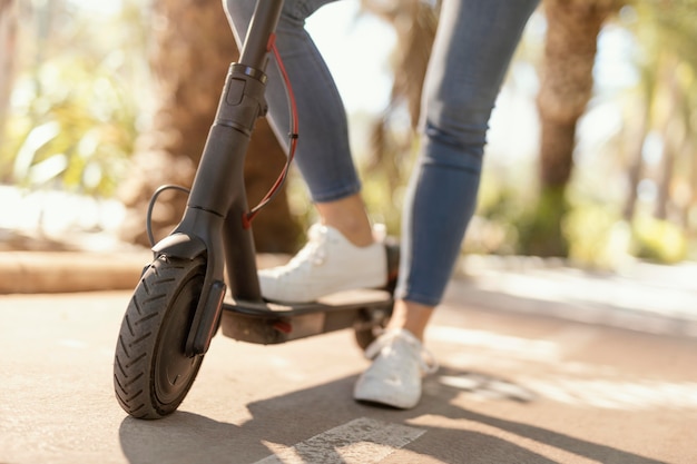 Mujer joven paseos en un scooter eléctrico en la ciudad