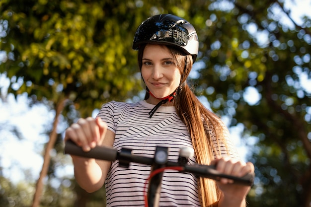 Mujer joven paseos en un scooter eléctrico en un parque