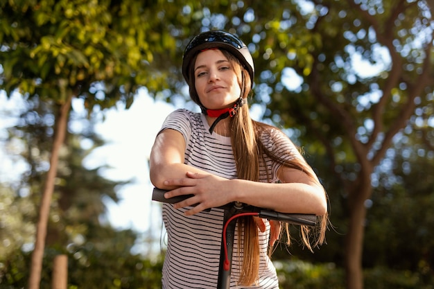 Mujer joven paseos en un scooter eléctrico en un parque