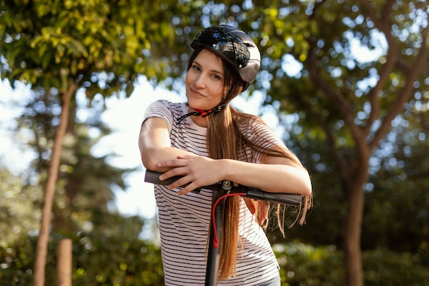Mujer joven paseos en un scooter eléctrico en un parque