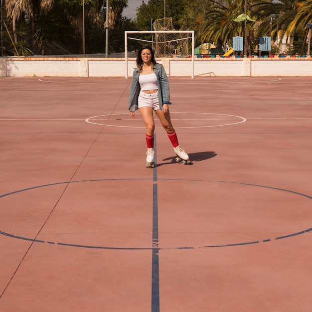 Mujer joven patinando en la cancha de fútbol al aire libre