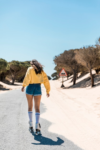 Mujer joven patinando sobre patines en forma pavimentada