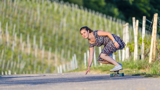 Mujer joven en patineta en una carretera vacía rodeada de vegetación