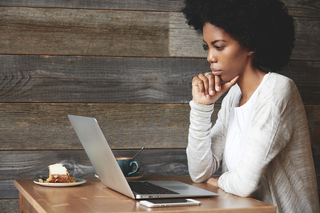 Mujer joven con peinado afro sentado en el café