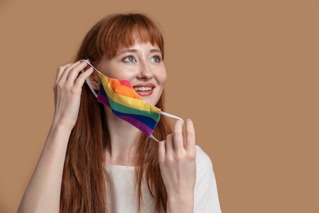 Mujer joven pelirroja con máscara médica arco iris