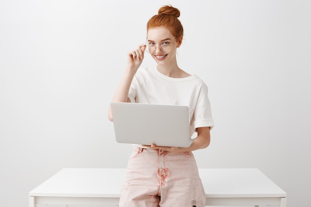 Mujer joven pelirroja trabajando con ordenador portátil, con gafas