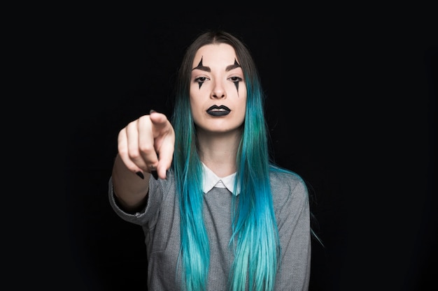 Mujer joven con pelo azul y maquillaje oscuro posando en estudio