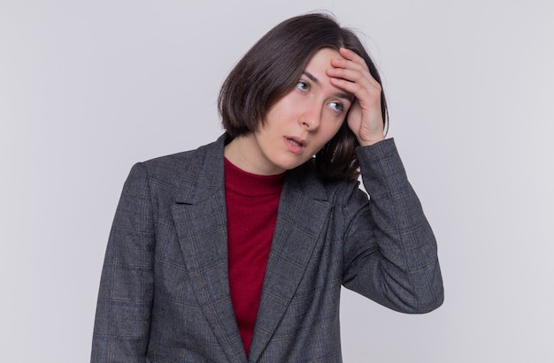 Mujer joven con pelo corto vistiendo chaqueta gris con aspecto cansado