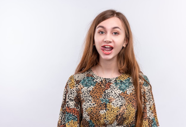 Mujer joven, con, pelo largo, llevando, colorido, sobresalir, lengua, posición, encima, pared blanca