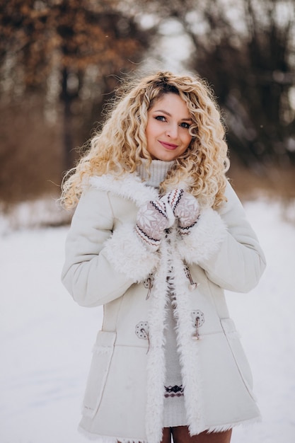 Mujer joven con pelo rizado caminando en un parque de invierno