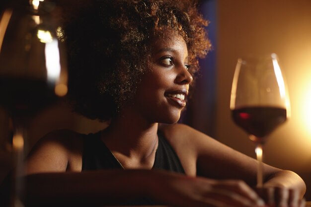 Mujer joven con pelo rizado y una copa de vino tinto