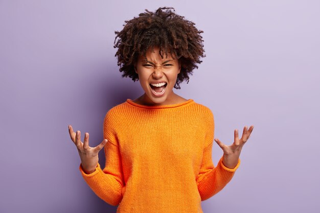 Mujer joven con pelo rizado vistiendo un suéter naranja