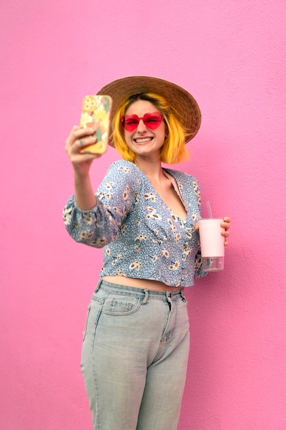 Foto gratuita mujer joven con el pelo teñido cerca de la pared rosa