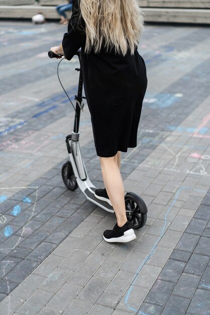 Mujer joven con pelos largos en scooter eléctrico. La niña en el scooter eléctrico.