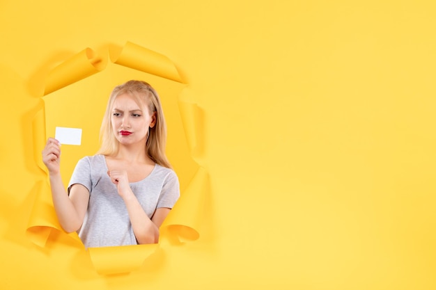 Mujer joven pensante con tarjeta de crédito sobre fondo amarillo venta de dinero facial de compras