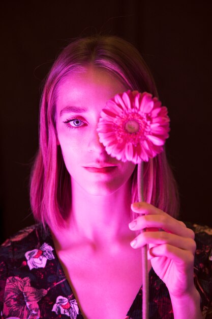 Mujer joven pensativa con gerbera rosa