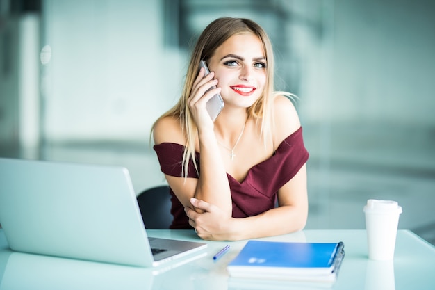 Mujer joven pensativa llamando al operador del software de actualización de soporte al cliente en la computadora portátil en la oficina. Freelancer serio concentrado en conversación telefónica sobre negocios en línea