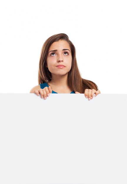 Mujer joven pensativa posando con un cartel en blanco