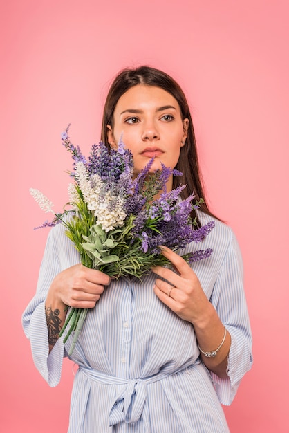 Foto gratuita mujer joven pensativa con ramo de flores