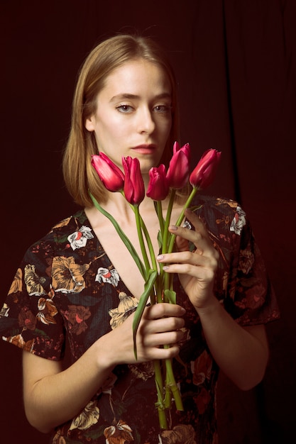 Mujer joven pensativa con tulipanes rojos